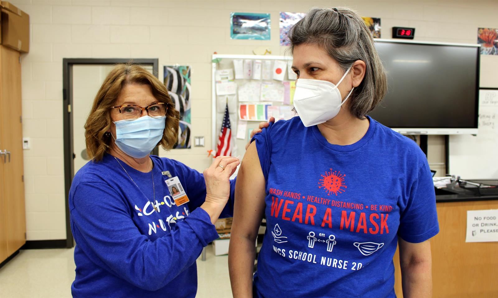 Nurse cleaning woman's arm for vaccination 